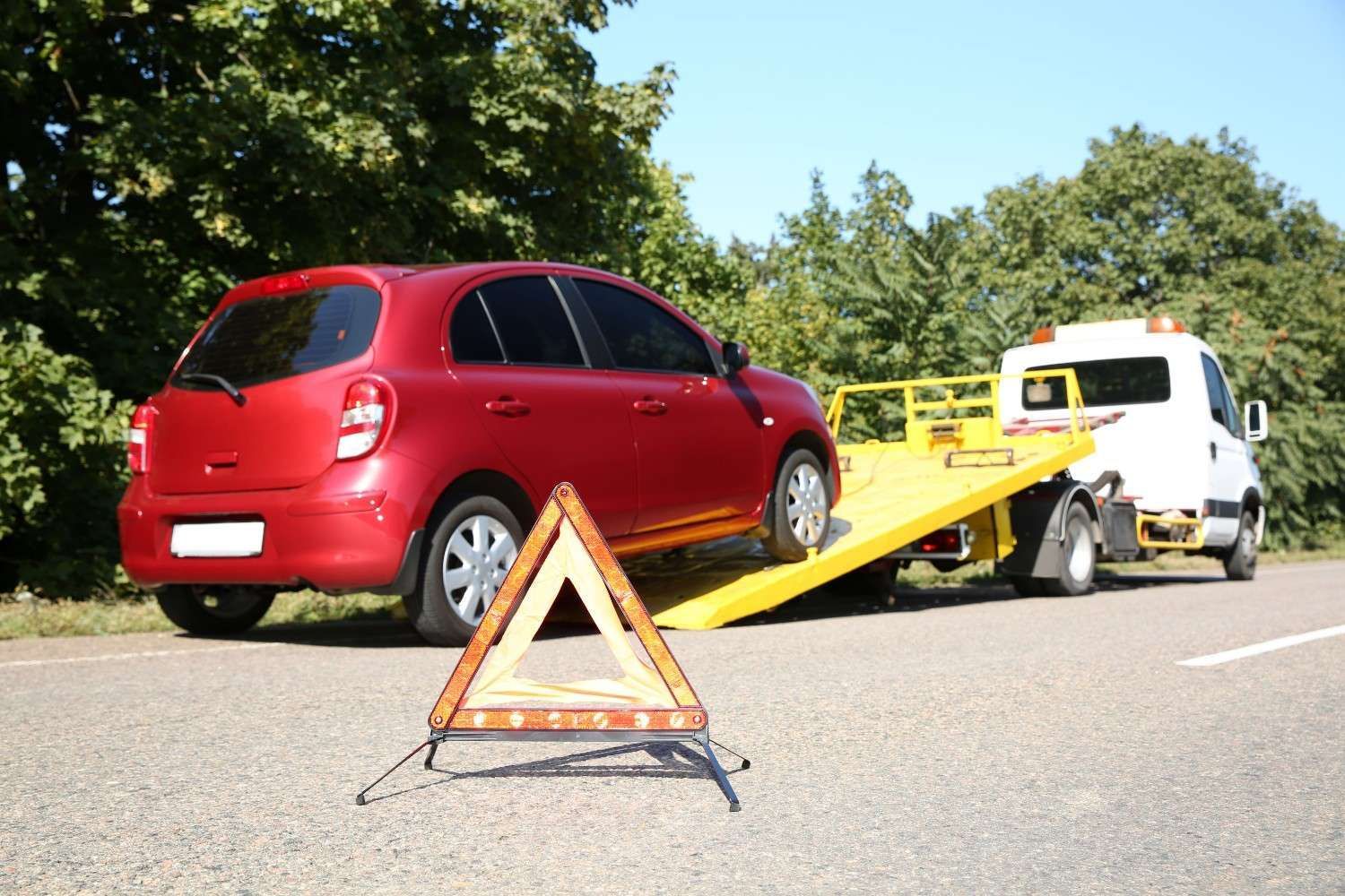 A Red Car Being Towed by A White Tow Truck on The Side of A Road — A1 Towing in Blue Haven, NSW
