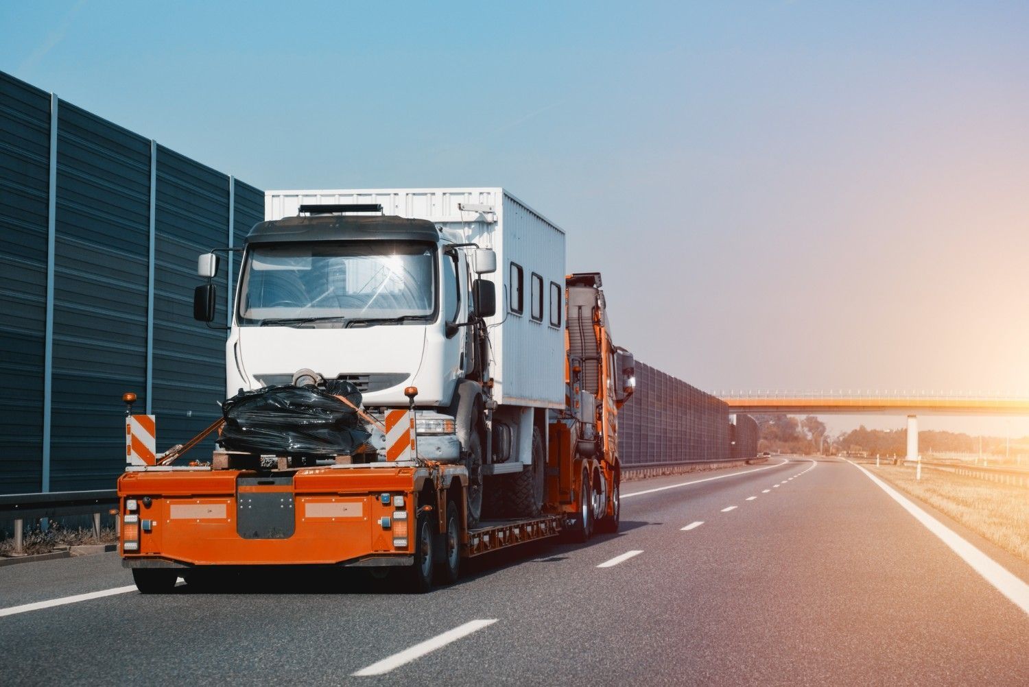 White Semi Truck Hauling an Orange Trailer on A Highway — A1 Towing in Newcastle, NSW