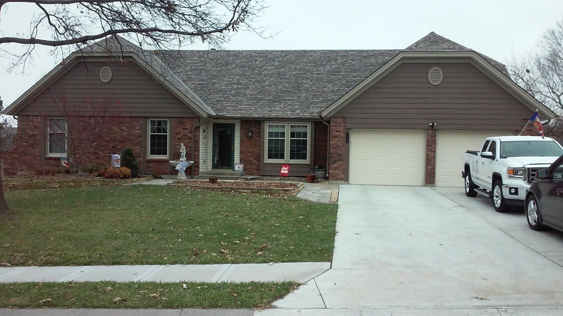A brick house with two cars parked in front of it