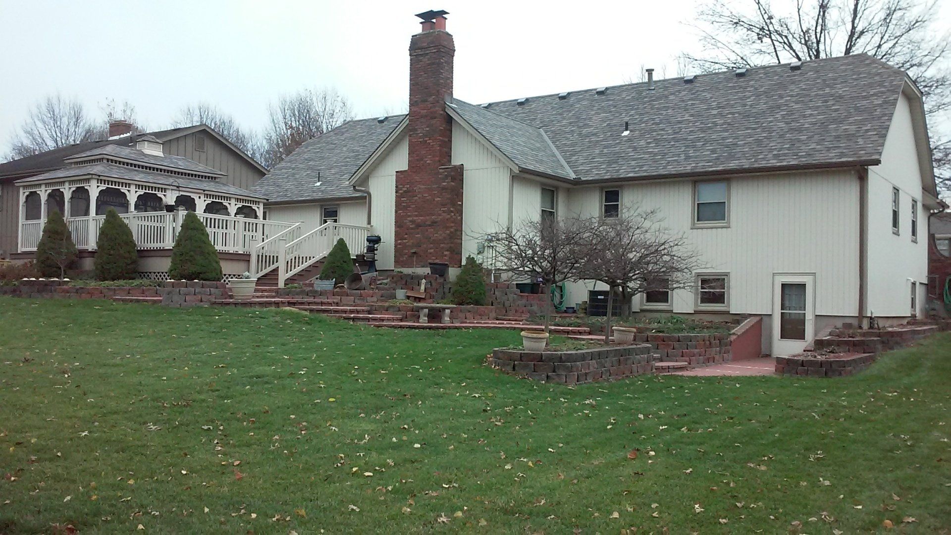 A large white house with a brick chimney in the backyard