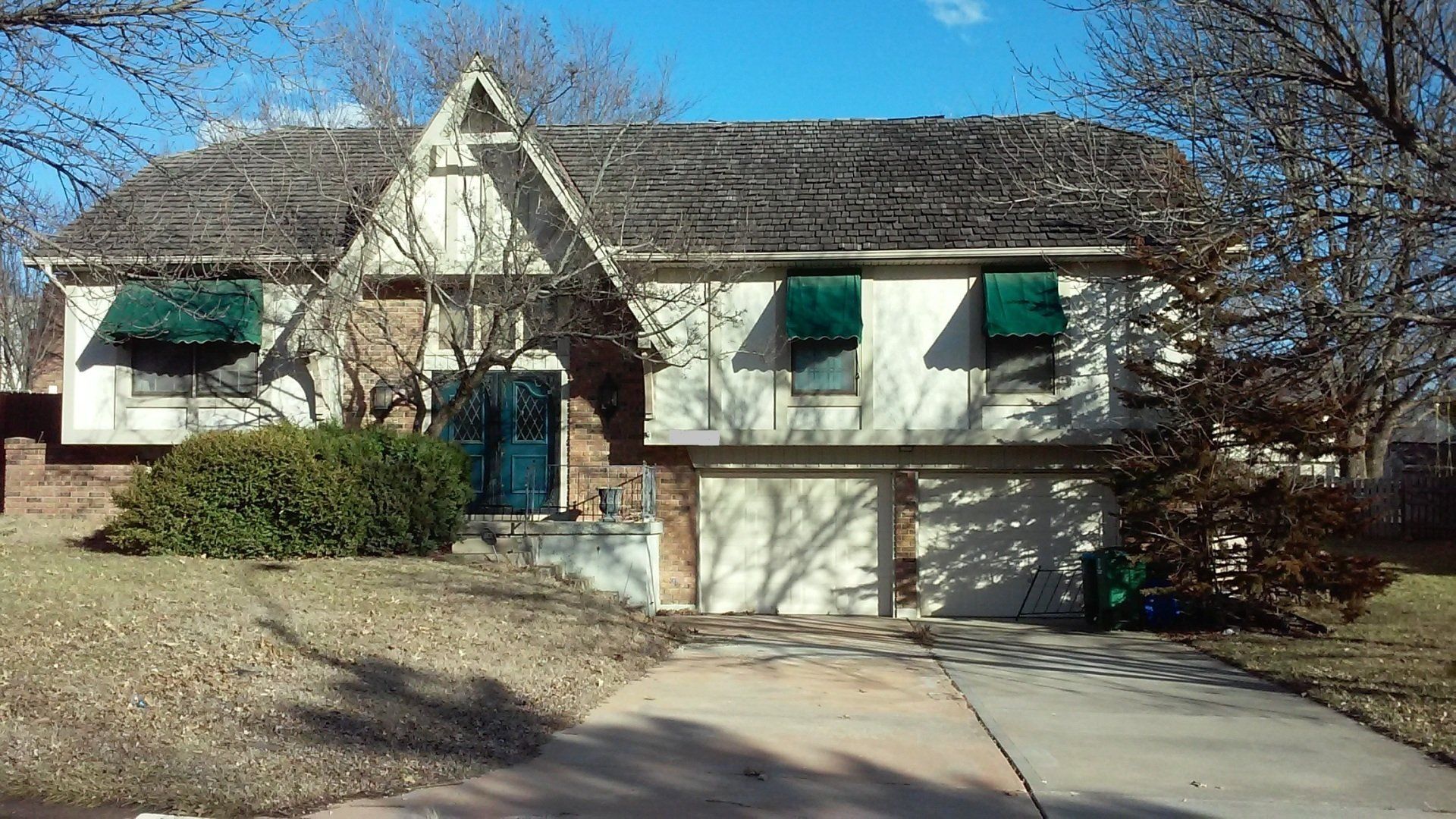 A white house with green awnings on the windows