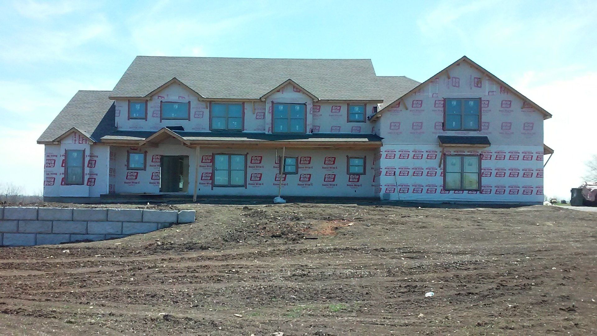 A large house is being built on top of a dirt hill.