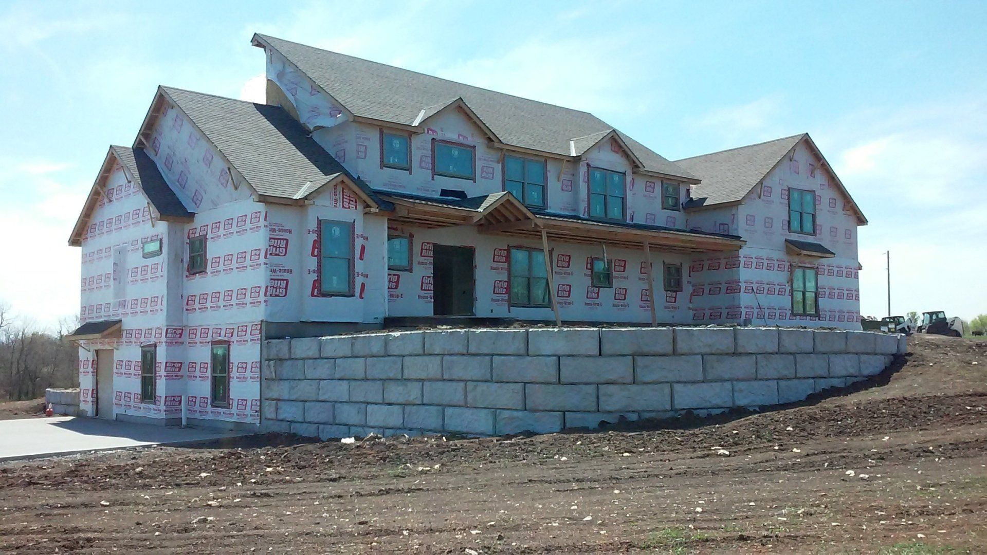A large house is being built in a dirt field