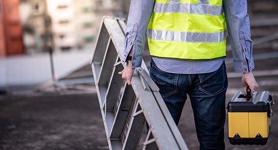 Worker carrying aluminium ladder and tool box — Raymore, MO — Meissen & Sons Roofing