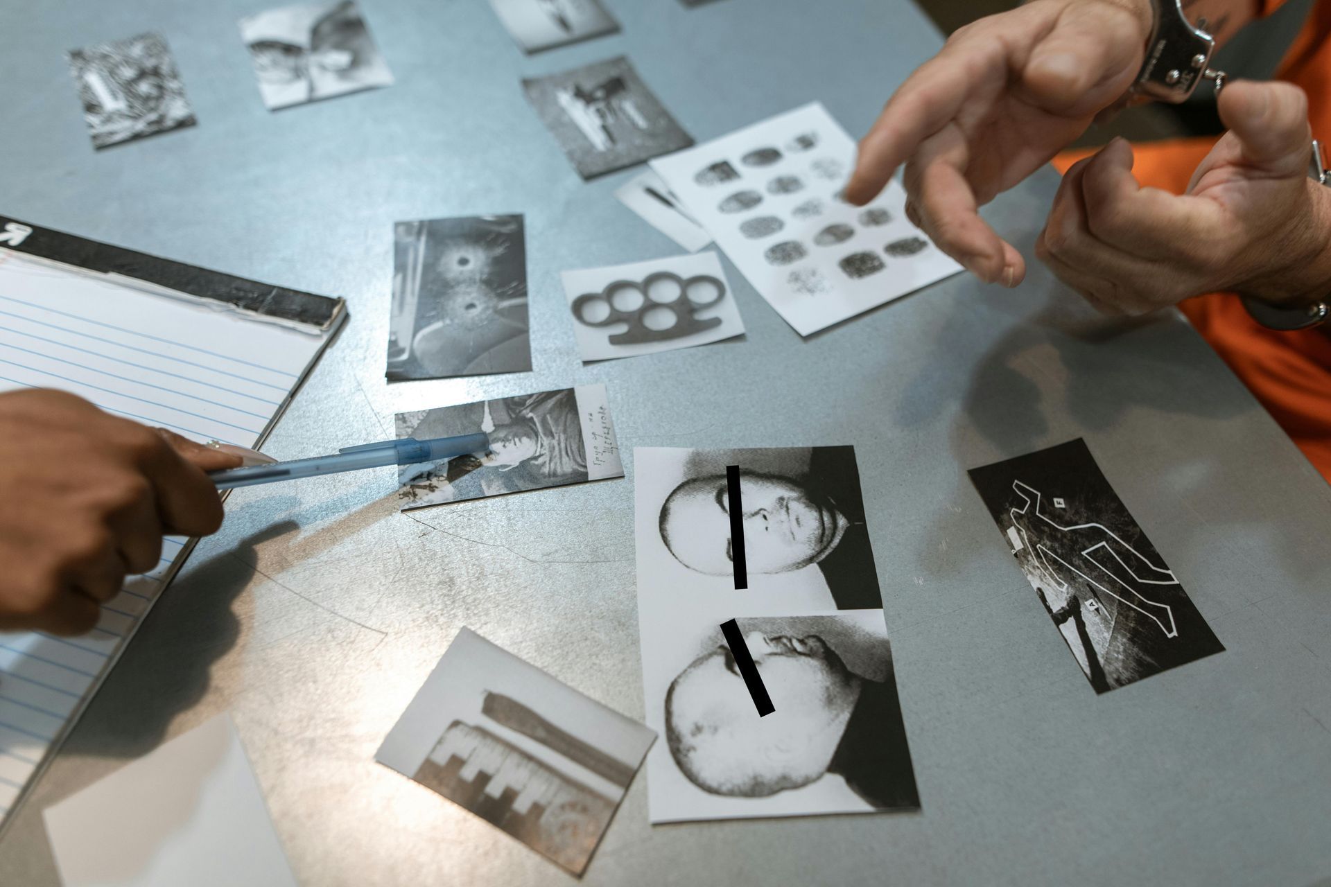 A man is pointing at a picture of a knuckle duster on a table.