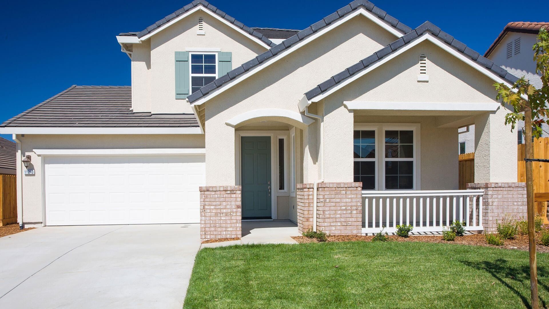 A white house with a white garage door and a porch.