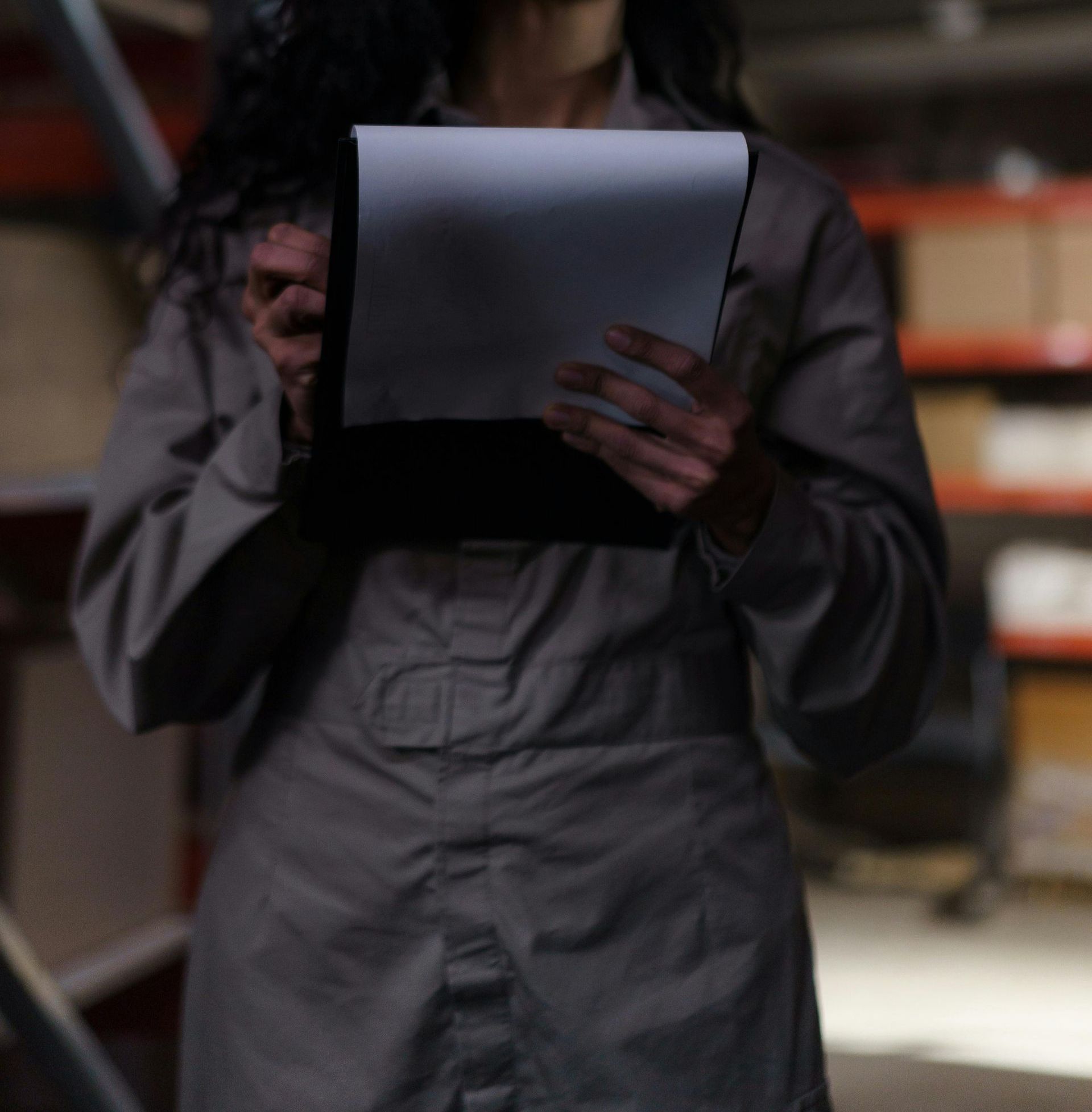 A woman in a grey shirt is holding a piece of paper