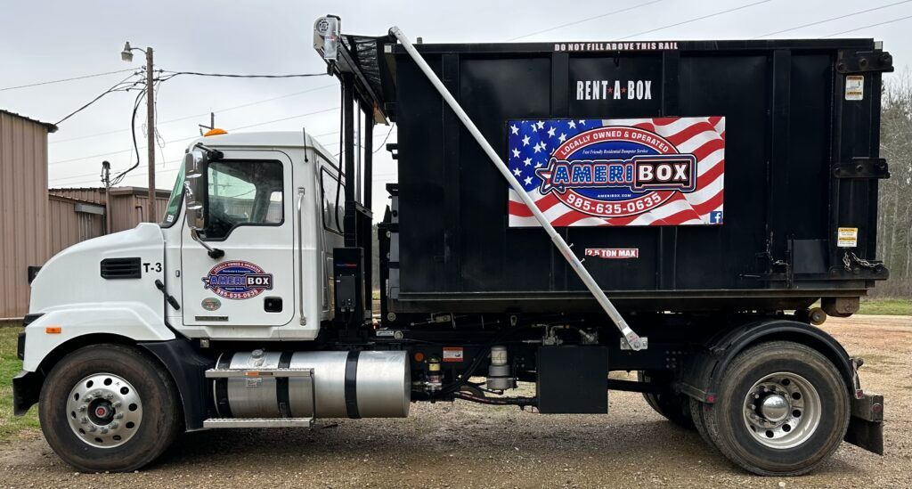 A picture of a dumpster truck carrying a dumpster on the back in Mandeville, LA