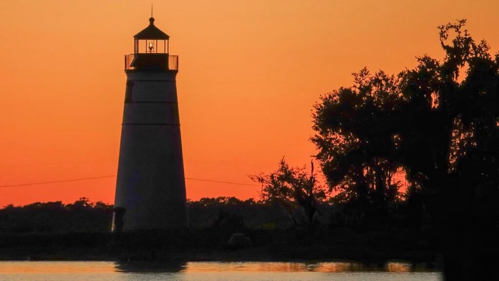 A picture of a lighthouse with a sunset in the background.