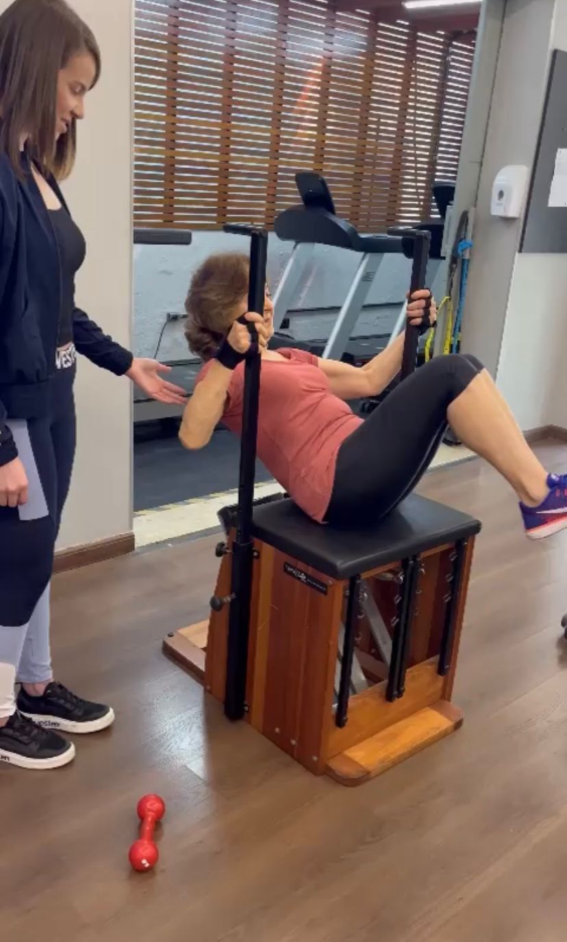 Uma mulher está fazendo exercícios em uma máquina de pilates em uma academia.