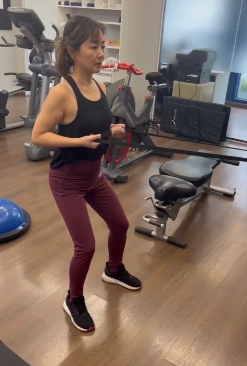 Uma mulher está fazendo agachamentos em uma academia.