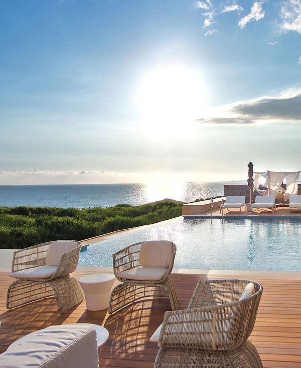 En swimmingpool omgivet af stole og borde med udsigt over havet