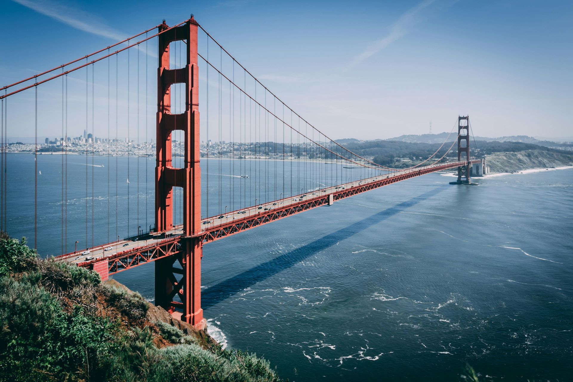 Two people are riding bicycles on a bridge in a city