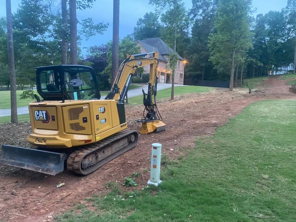A cat excavator is sitting on the side of a dirt road.