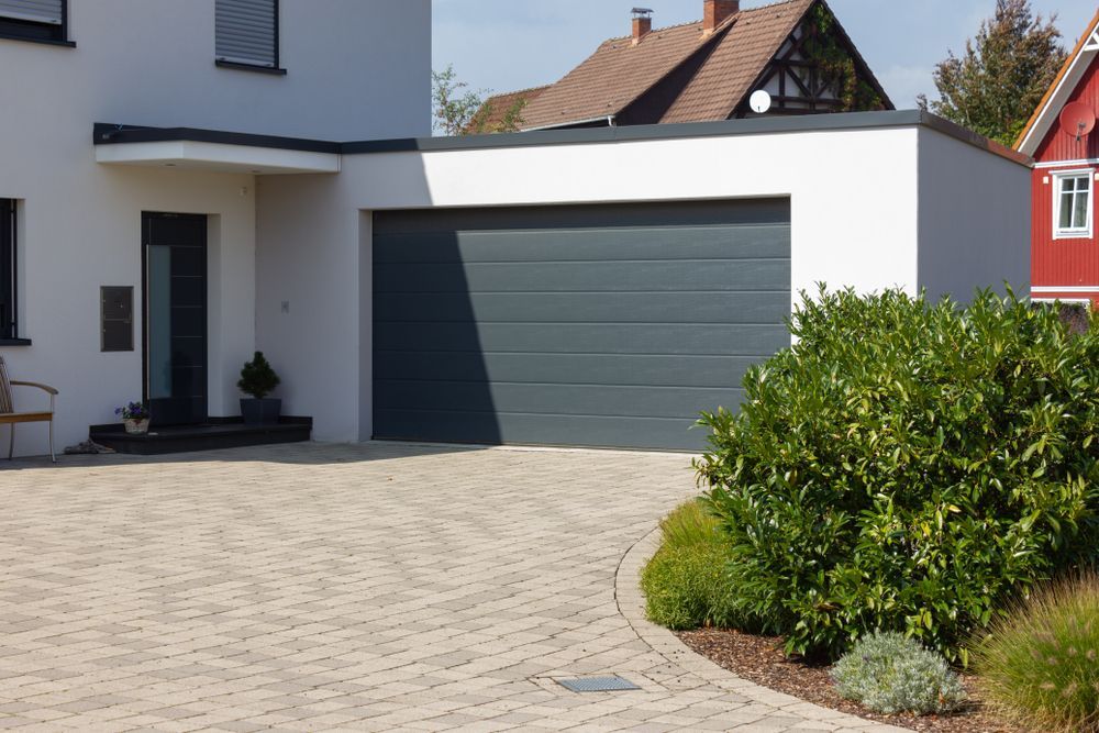 Modern White House With a Gray Garage Door, Driveway, and Landscaping — Atherton Tableland Concreting in Yungaburra, QLD