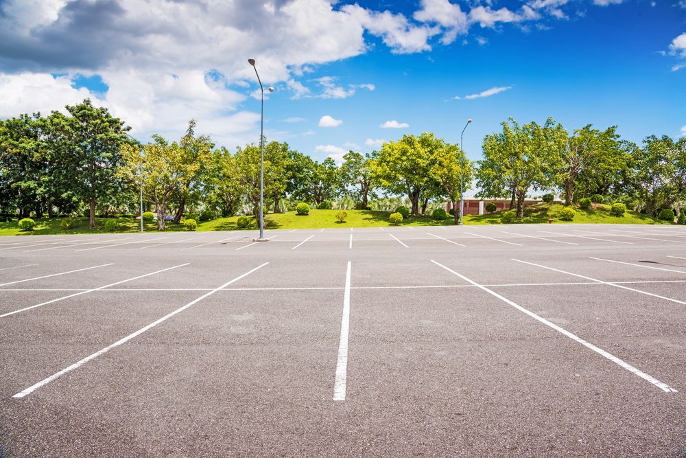 Empty Parking Lot With White Lines, Trees, and Blue Sky With Clouds — Atherton Tableland Concreting in Yungaburra, QLD