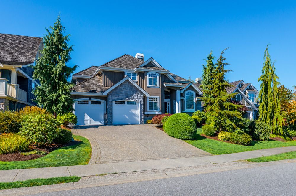 Two-story House With Gray Siding, White Garage Doors, and a Paved Driveway — Atherton Tableland Concreting in Yungaburra, QLD