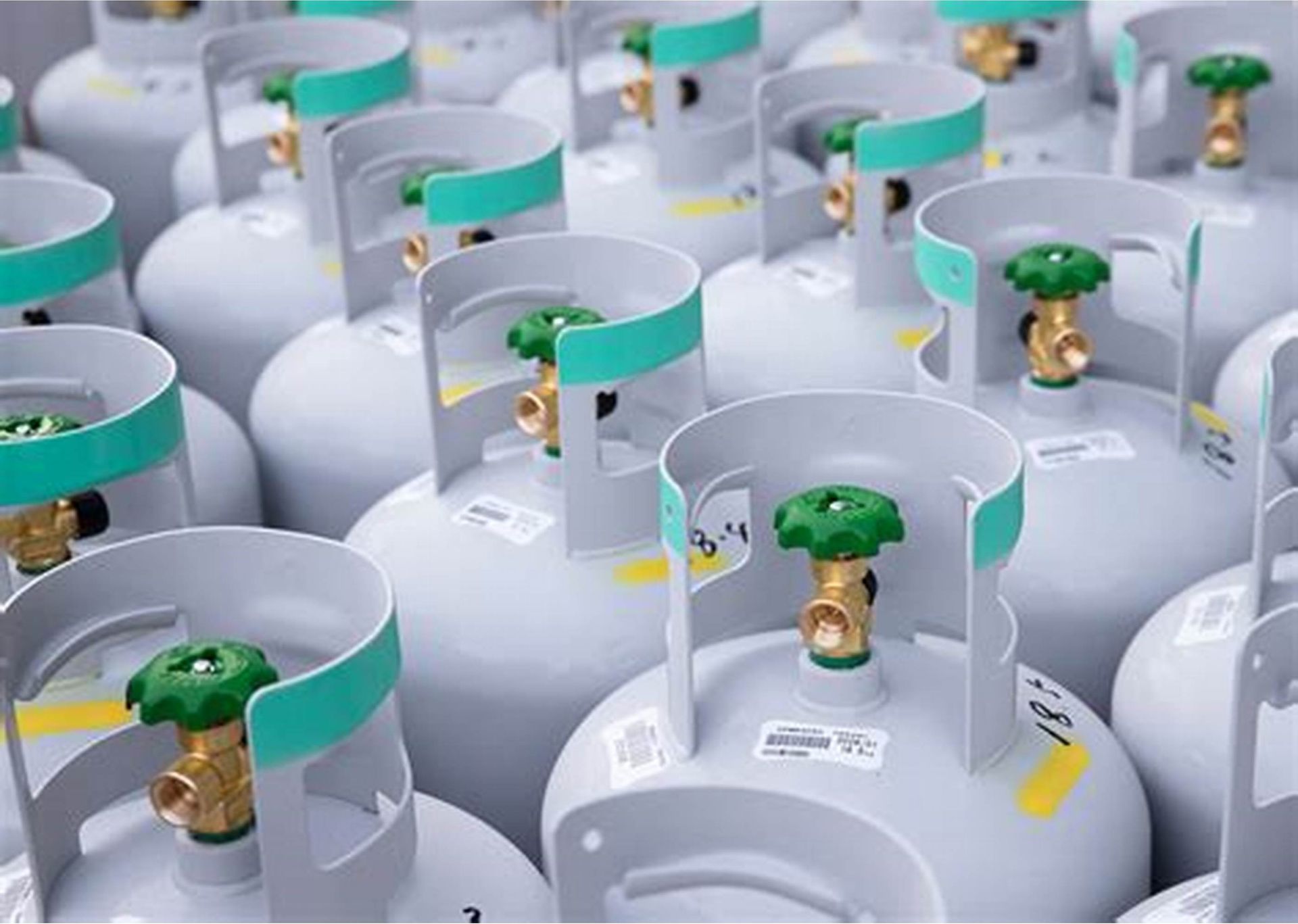 Een aantal gasflessen met groene ventielen staan ​​op een rij.