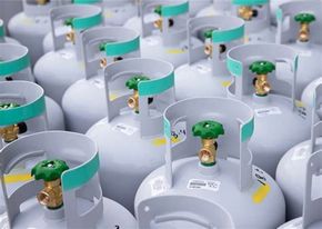 Een aantal gasflessen met groene ventielen staan op een rij.