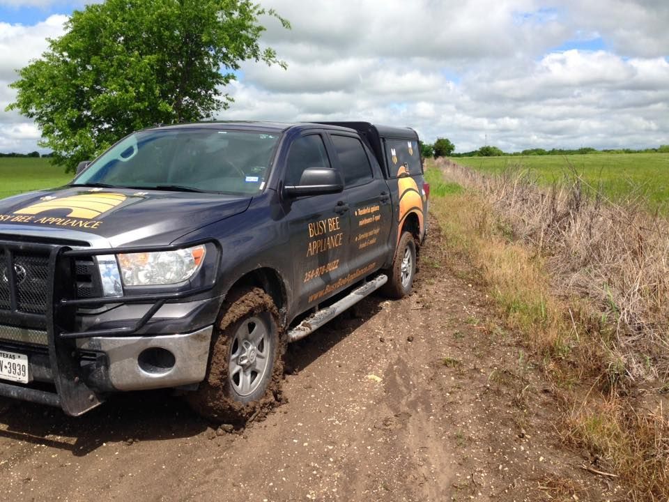 A truck is stuck in the mud on a dirt road.
