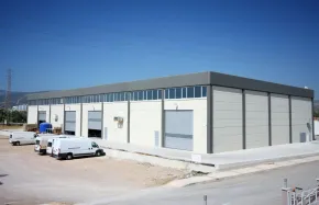 Warehouse with several loading bays, white walls, and a flat roof, parked delivery vans.