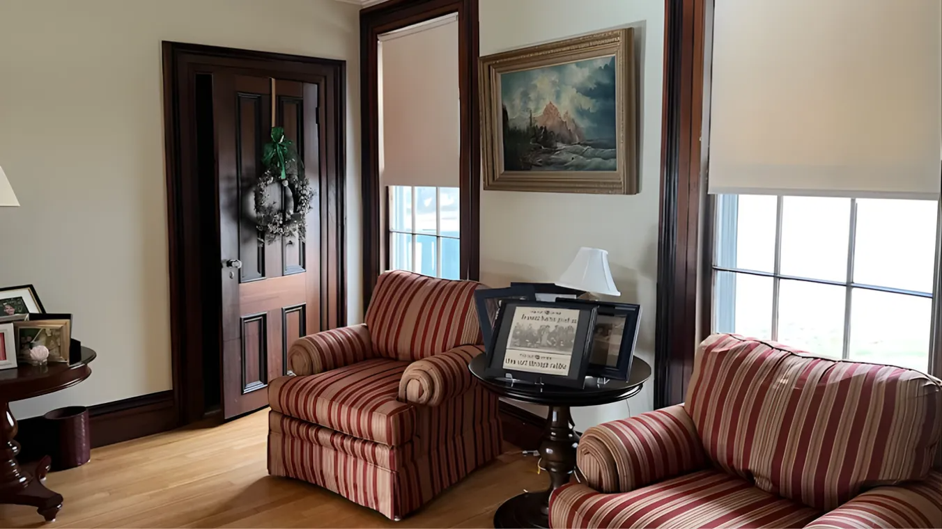 Cozy living room with two striped armchairs, wood floor, front door, and windows with blinds.