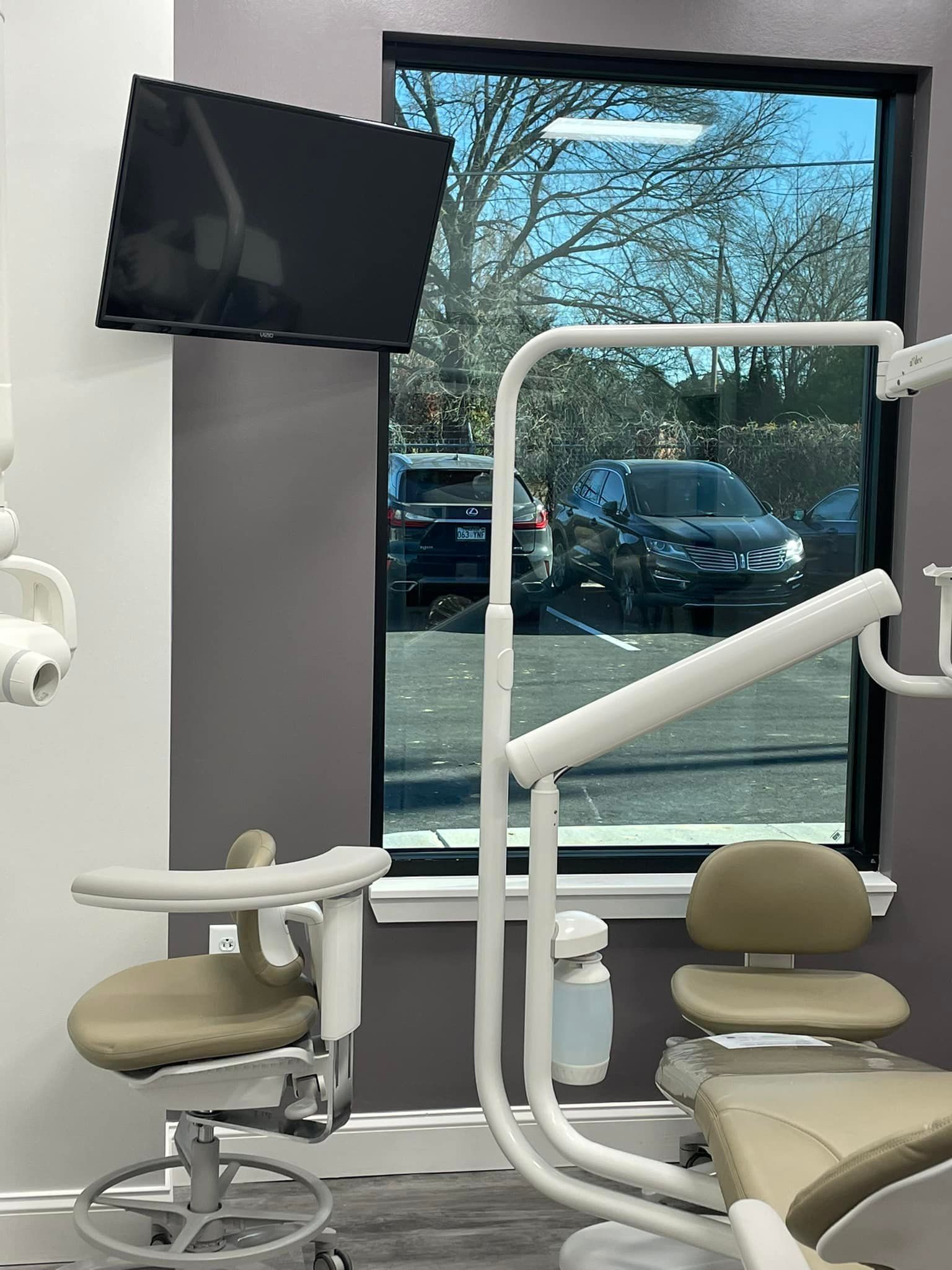 A dental office with a dental chair and a television on the wall.
