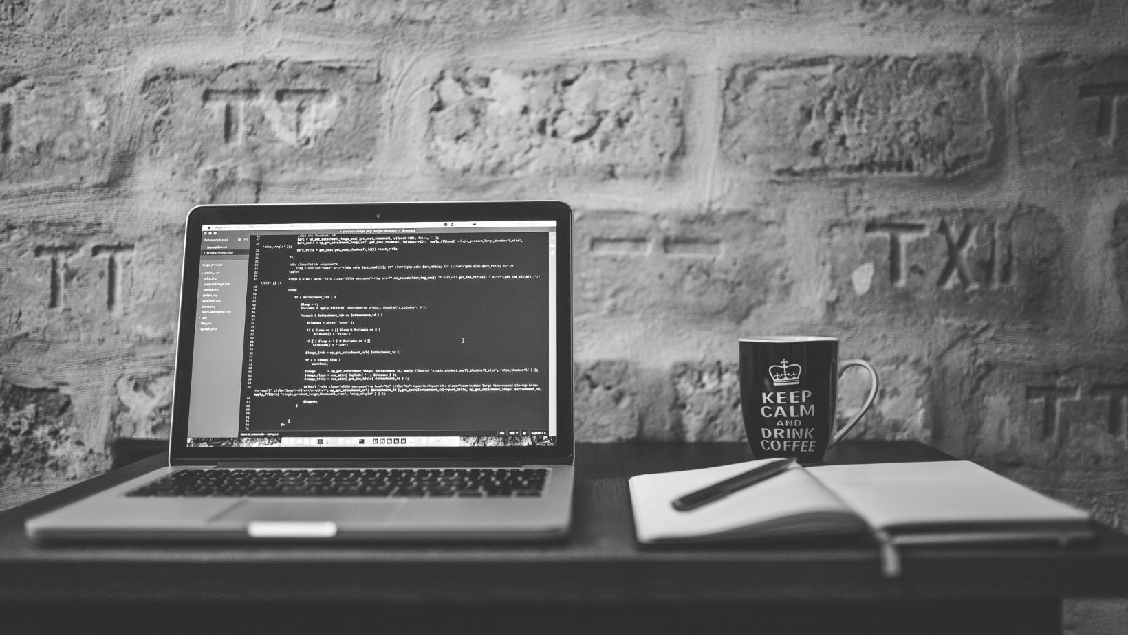A laptop computer is sitting on a desk in front of a brick wall.