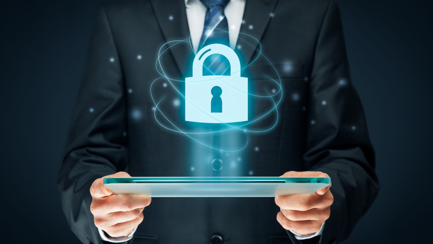 A man in a suit is holding a tablet with a padlock coming out of it.