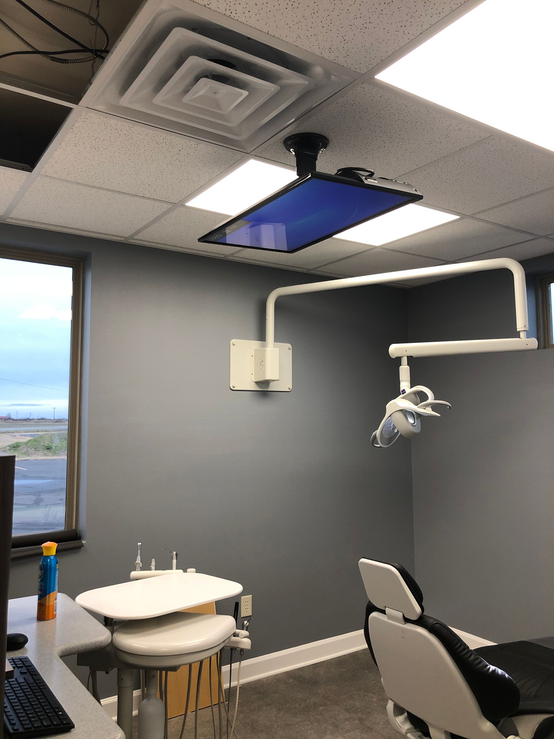 A dental office with a dental chair and a monitor on the ceiling