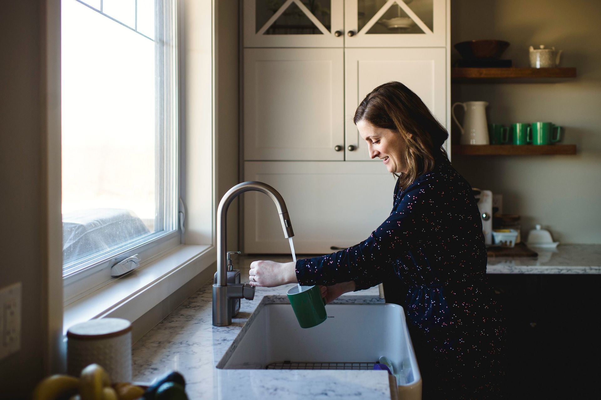 Johnny Jones Plumbing - A woman is washing dishes in a kitchen sink.