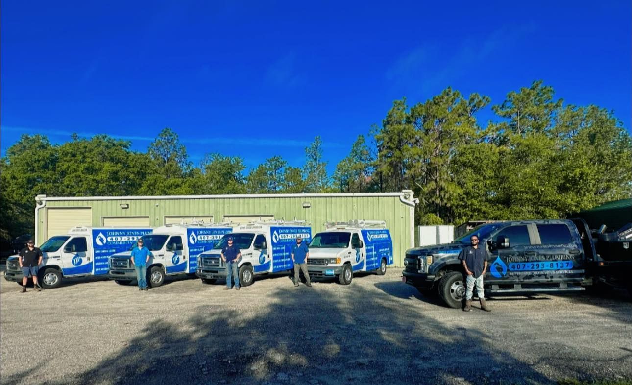 Johnny Jones Plumbing - A group of people standing in front of a row of trucks.