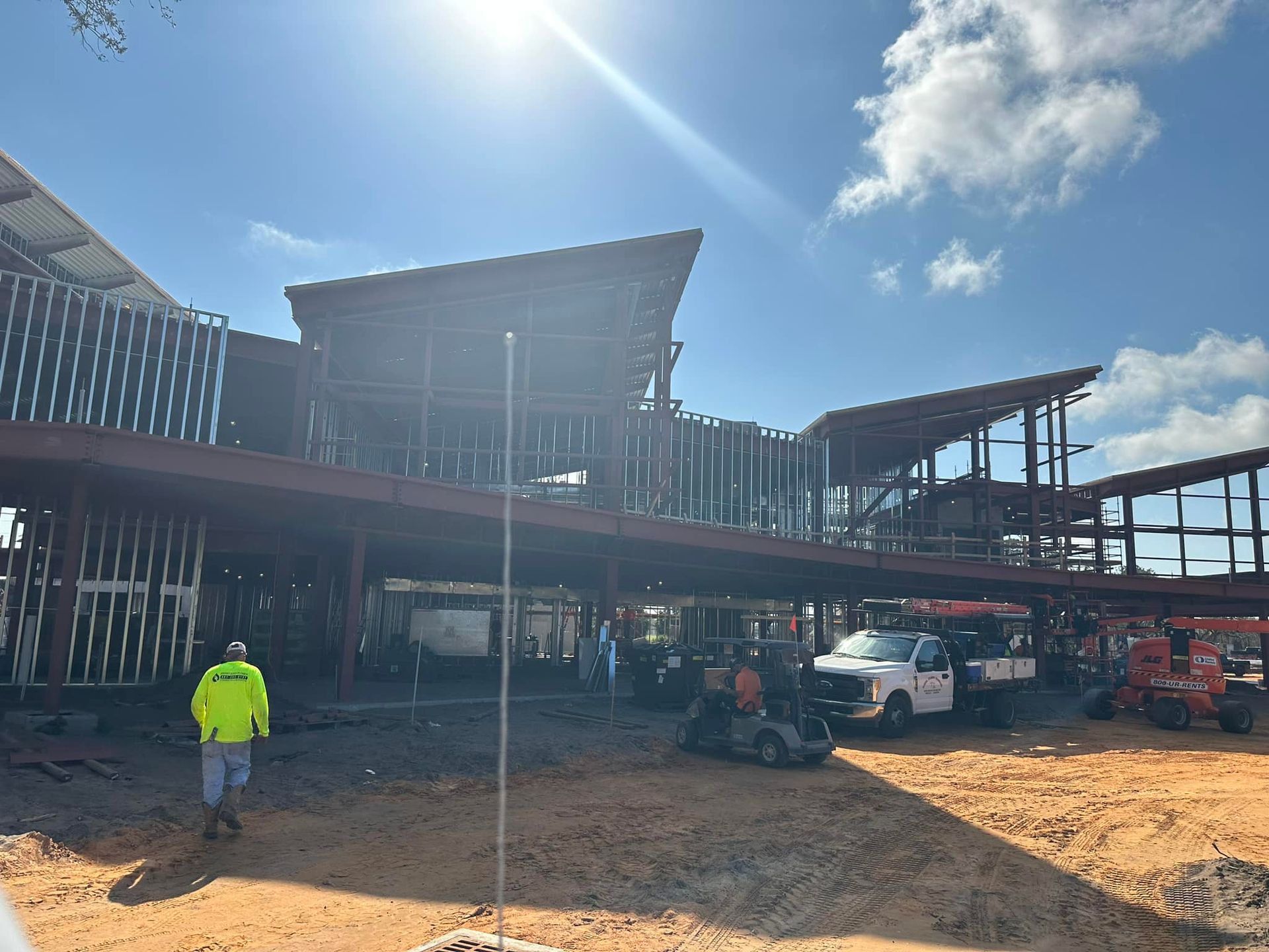 Johnny Jones Plumbing - A man in a yellow jacket is standing in front of a building under construction.