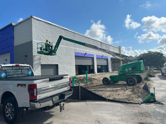 A white truck is parked in front of a building under construction.
