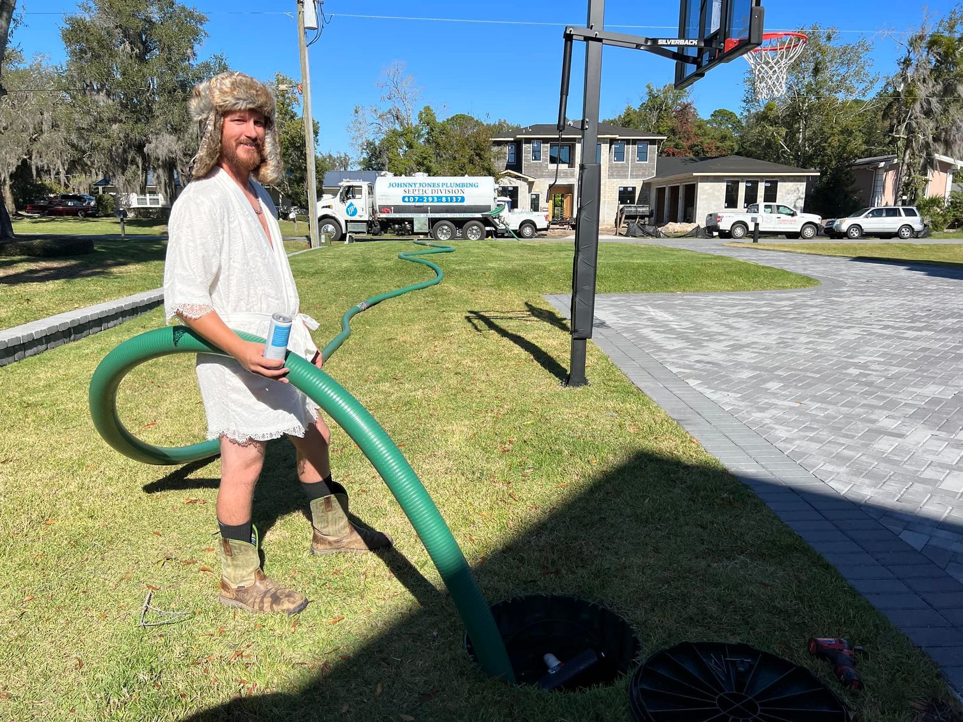 Johnny Jones Plumbing - A man is standing in the grass holding a green hose.