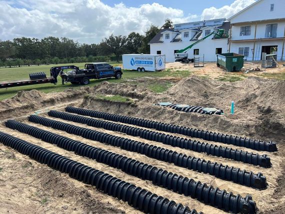A septic system is being built in the dirt in front of a house.
