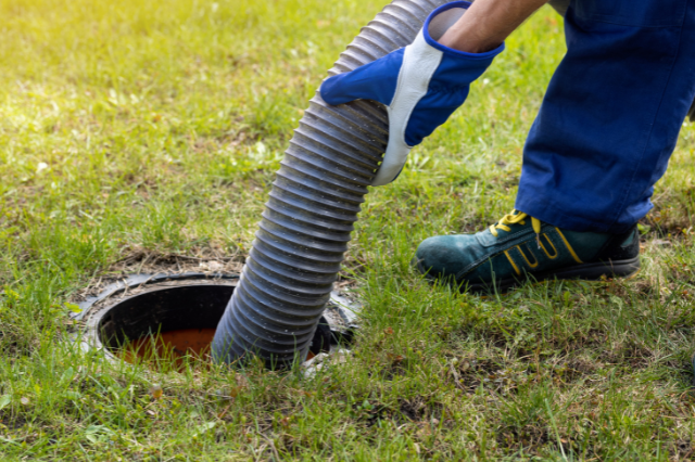 A person is pumping a hose into a septic tank.
