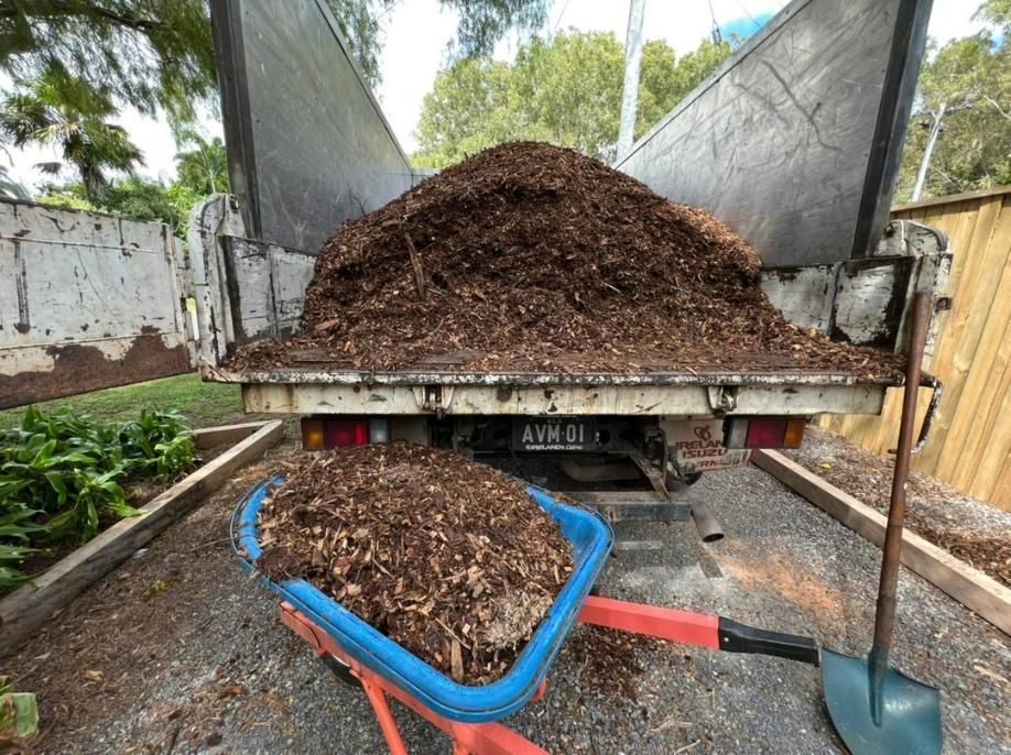 A Wheelbarrow Is Sitting in Front of A Truck Filled with Mulch — Advanced Vegetation Management in Smithfield, QLD