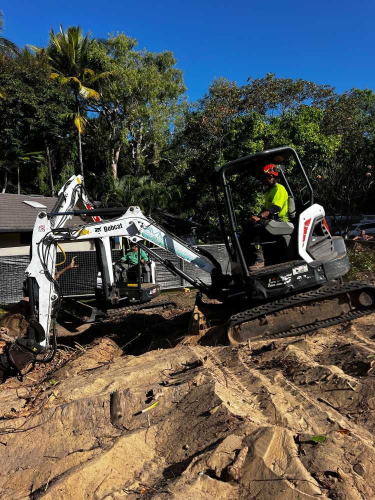 A Man is Driving a Small Excavator in a Dirt Field — Advanced Vegetation Management in Stratford, QLD
