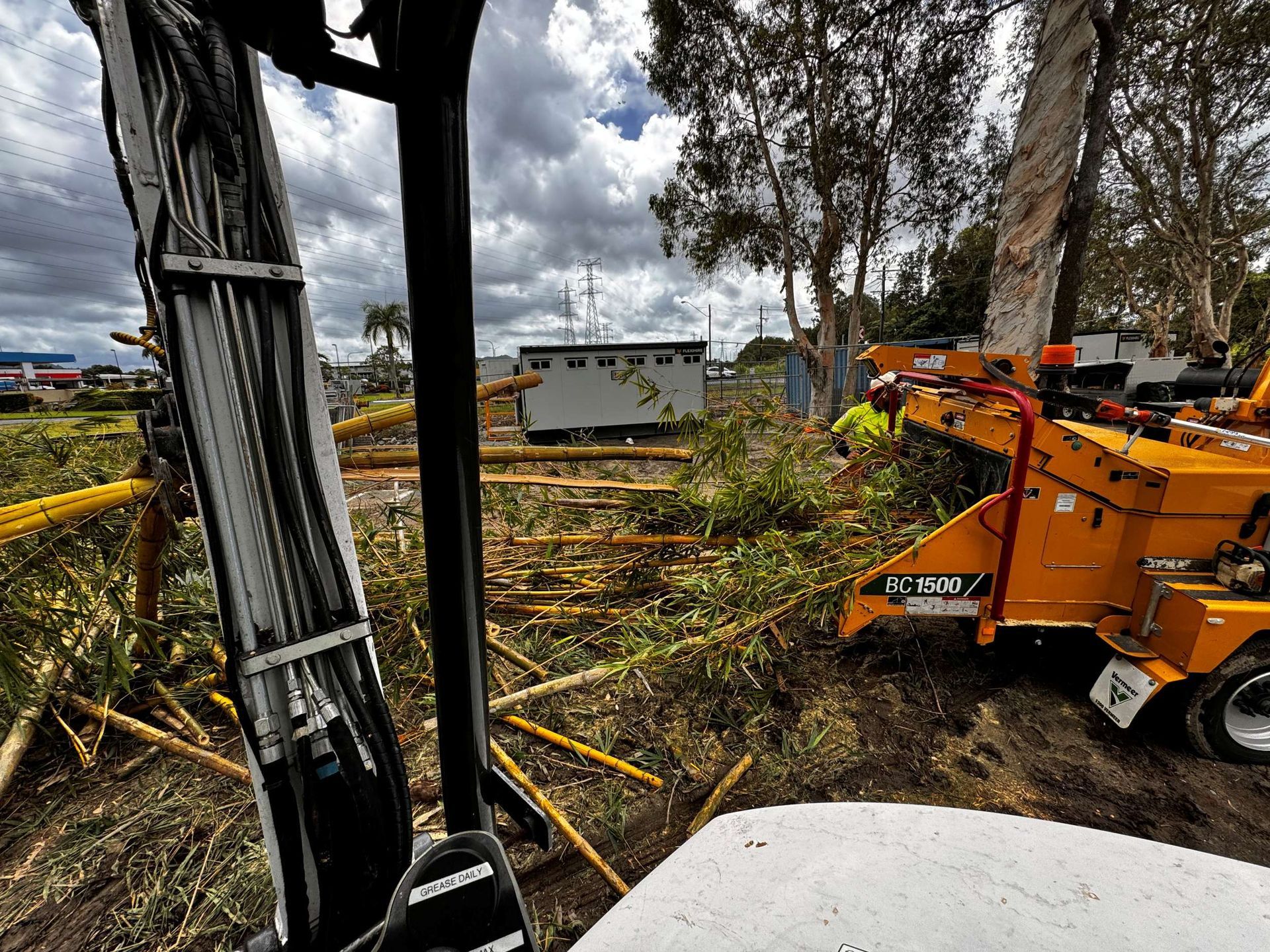 A Crane is Sitting in the Middle of a Field Next to a Tree Chipper — Advanced Vegetation Management in Clifton Beach, QLD