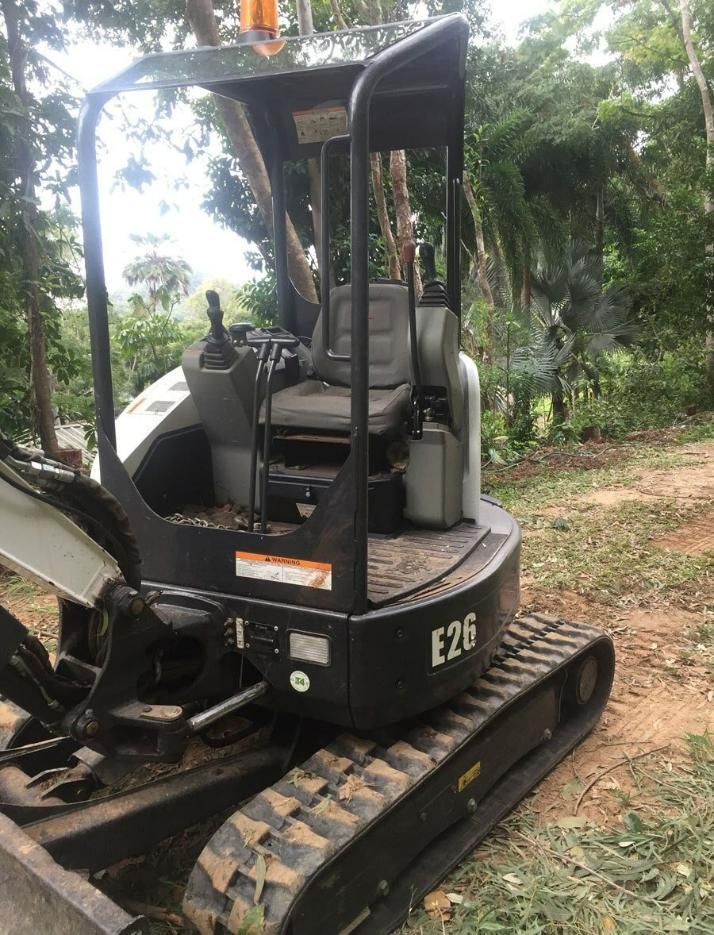 A Small Excavator Is Parked on A Dirt Road in The Woods — Advanced Vegetation Management in Stratford, QLD