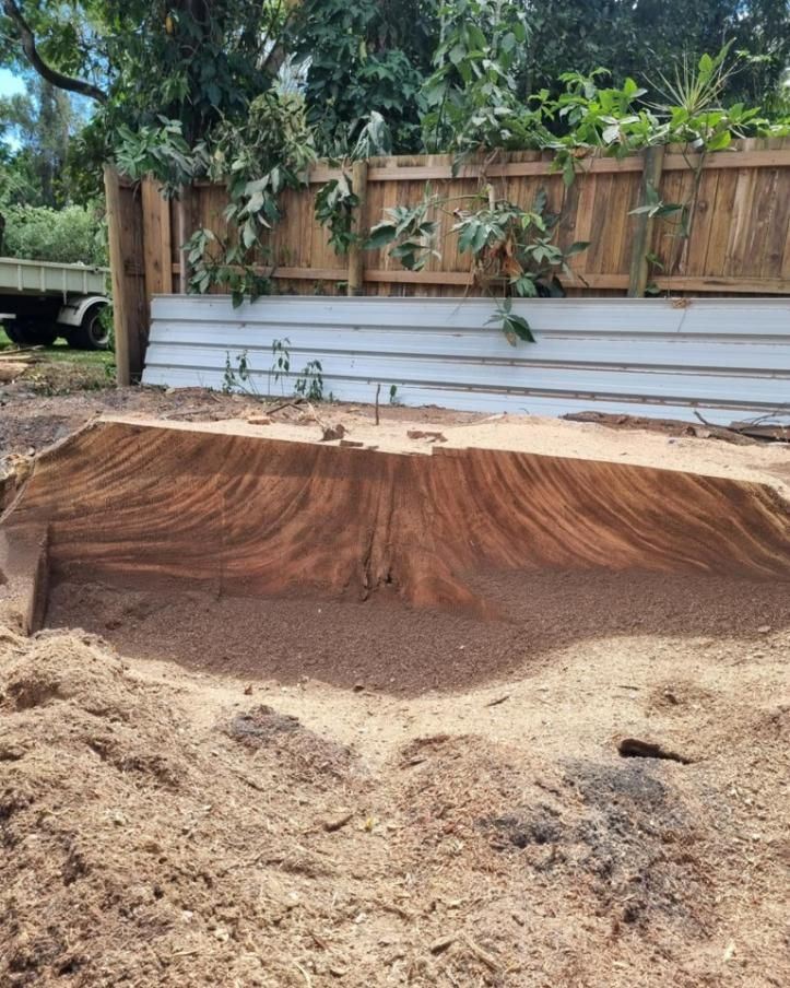 A Large Pile of Dirt Is Sitting in Front of A Wooden Fence — Advanced Vegetation Management in Stratford, QLD