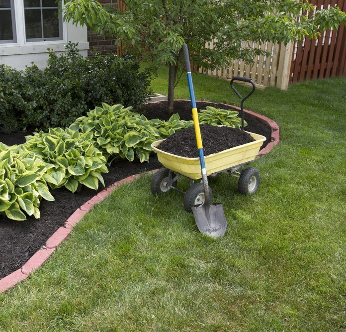 A Yellow Wheelbarrow Filled With Dirt and a Shovel — Dubbo Soils & Landscaping Supplies in Wellington, NSW