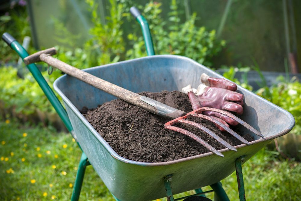 Pitch Fork and Gardening Gloves Laying on a Cart Full of Soil — Dubbo Soils & Landscaping Supplies in Dubbo, NSW
