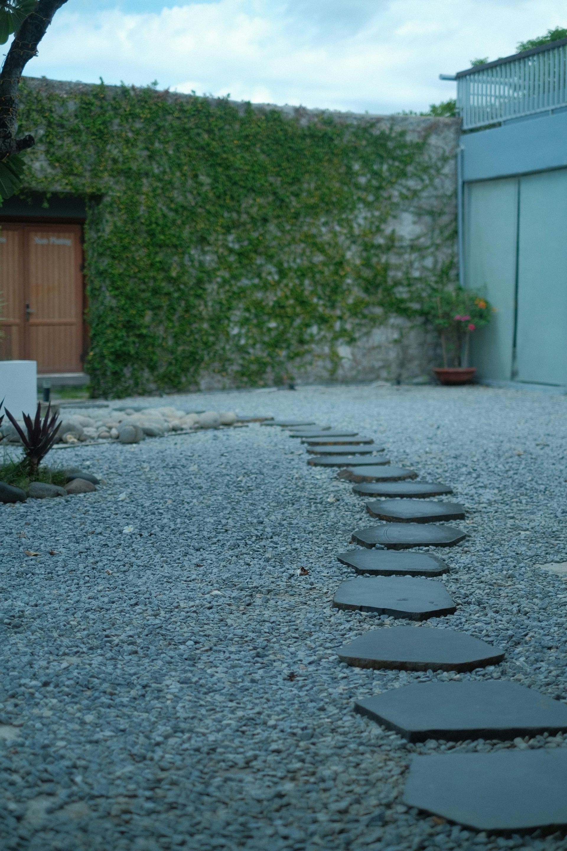 A Stone Wall Surrounds a Lush Green Lawn in Front of a House — Dubbo Soils & Landscaping Supplies in Narromine, NSW