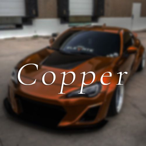 A copper car is parked in front of a building