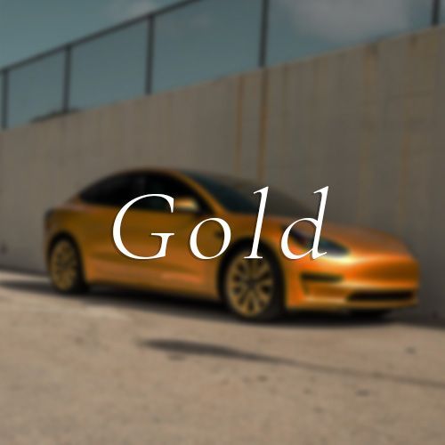 A gold car is parked in front of a concrete wall