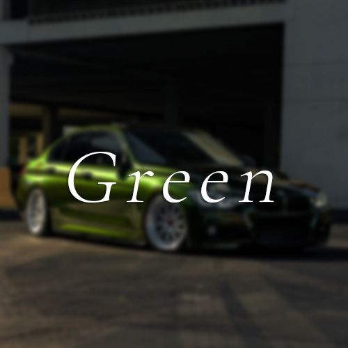 A green car is parked in front of a building with the word green written on it.