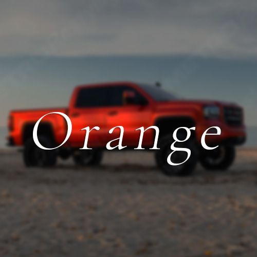 A red truck is parked on a beach with the word orange above it