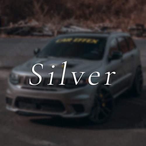 A silver car is parked on the side of the road.